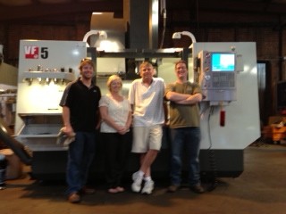 A group of machinists beside a CNC equipment